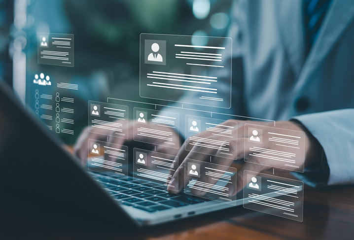 A person working on a laptop with a digital HR dashboard displaying candidate profiles and analytics, representing online recruitment, workforce management, and modern human resources technology.