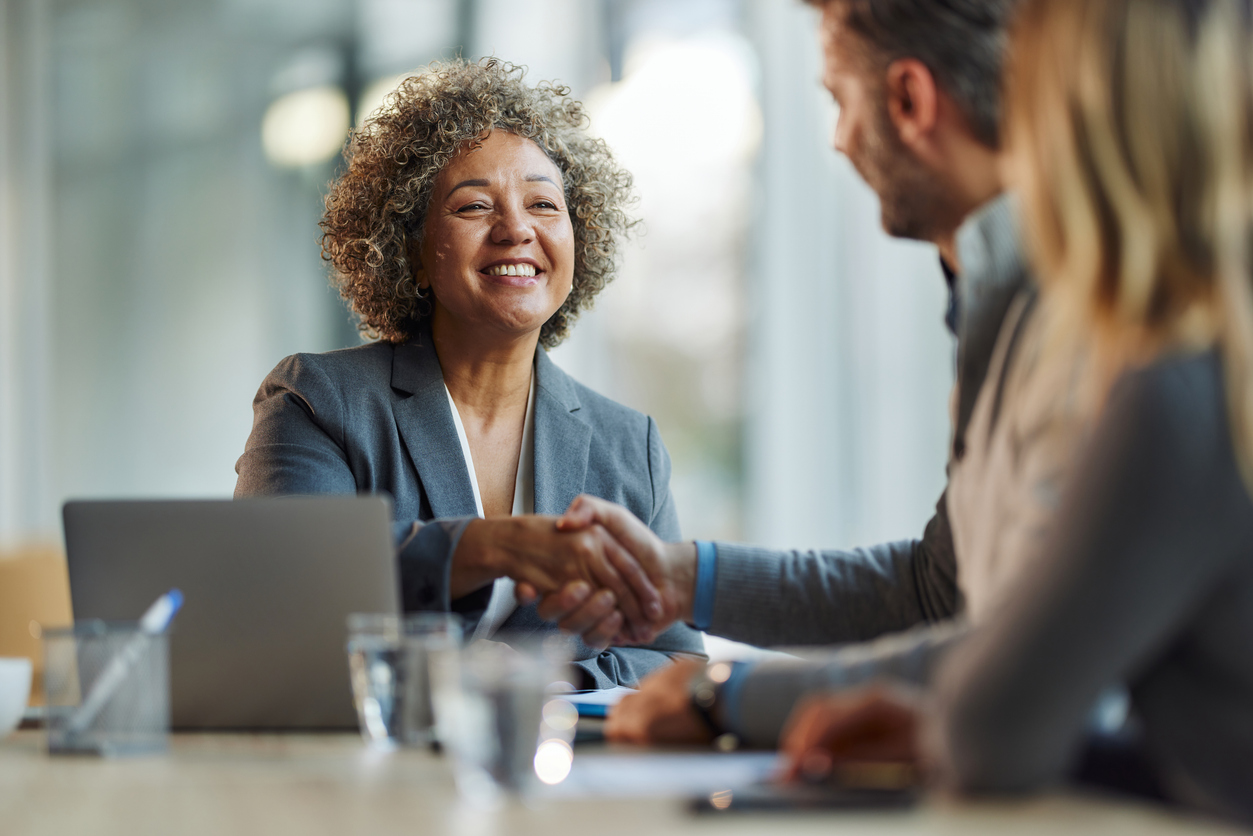 Happy insurance agent shaking hands with her customers in the office.