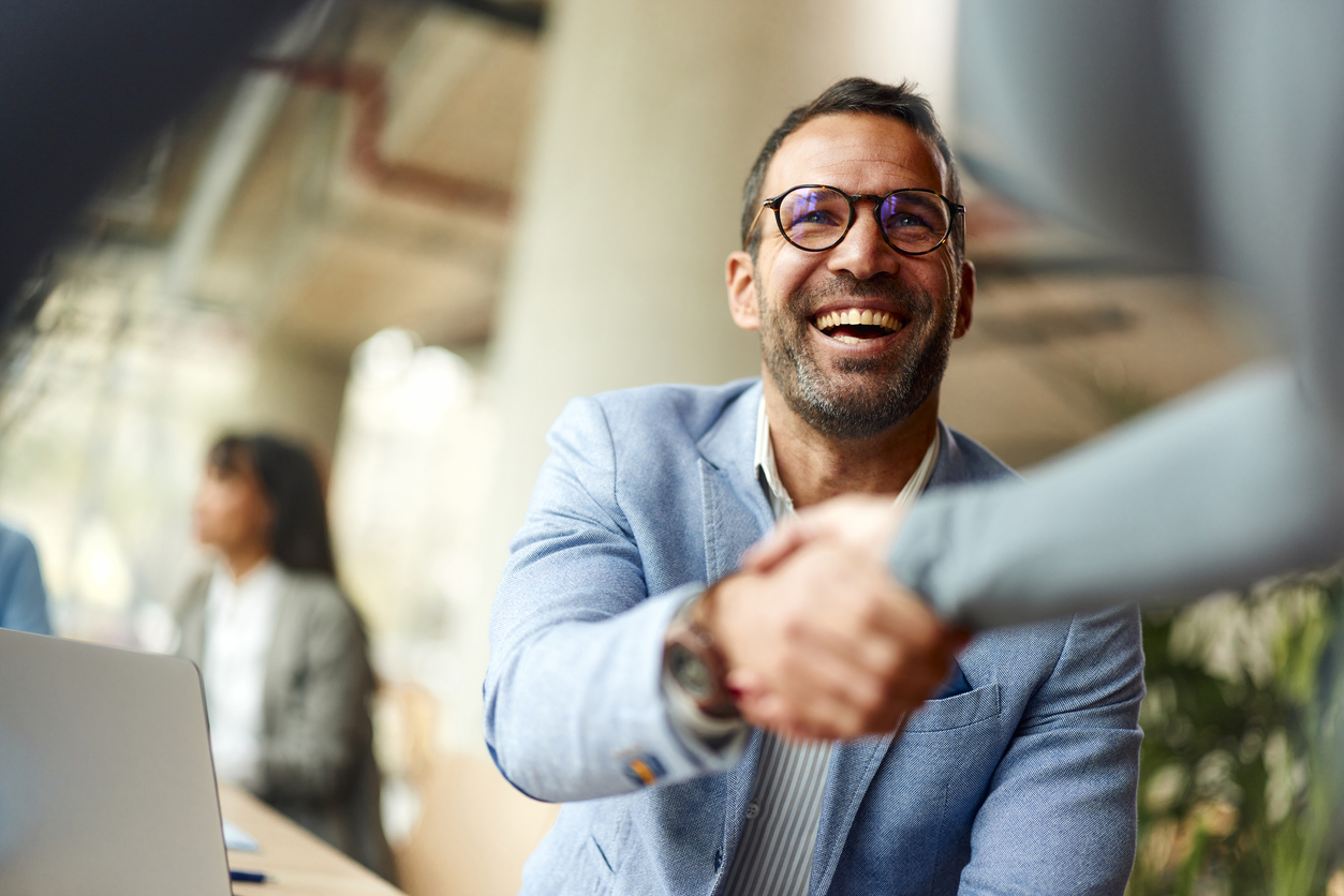 Happy businessman shaking hands with his colleague on a meeting in the office.